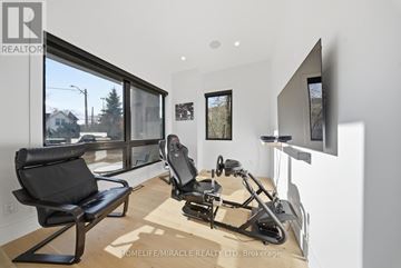 Mississauga (Mineola) apartment for rent - A modern living room with a black chair and a black exercise bike.