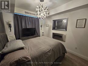 Barrie (Holly) condo for rent - A bedroom with a large bed and a chandelier.