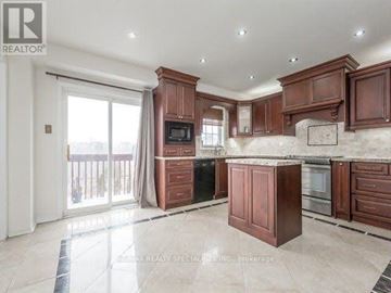 Brampton (Fletcher's Meadow) apartment for rent - A well-lit kitchen with wooden cabinets and a tiled floor.