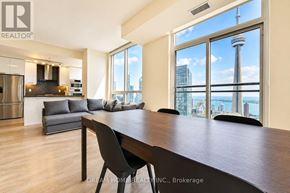 Toronto (Waterfront Communities) condo for rent - A modern kitchen with a dining table and chairs in front of a large window overlooking the city.