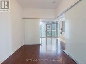 Toronto (Waterfront Communities) condo for rent - A room with wooden floors and white walls, with a glass door leading to a balcony.