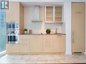 Toronto (Waterfront Communities) condo for rent - A kitchen with beige cabinets and a stainless steel oven.