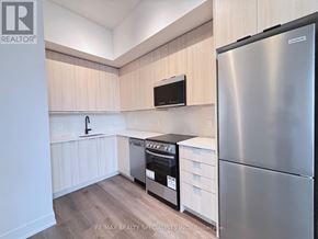 Milton (Tm Timberlea) condo for rent - A modern kitchen with a stainless steel refrigerator and wooden cabinets.