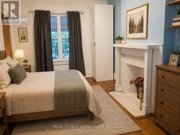 Toronto (Dovercourt-Wallace Emerson-Junction) apartment for rent - A bedroom with a bed, a fireplace, and a painting on the wall.