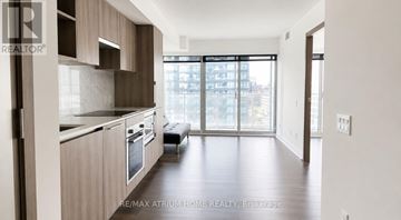 Toronto (Waterfront Communities) condo for rent - A modern kitchen with wooden cabinets and a large window.