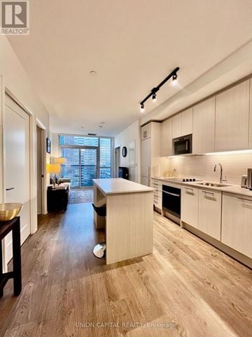 Toronto (East End-Danforth) condo for rent - A modern kitchen with white cabinets and a wooden floor.