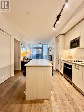 Toronto (East End-Danforth) condo for rent - A kitchen with wooden floors and white cabinets.