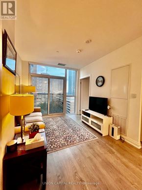Toronto (East End-Danforth) condo for rent - A living room with a television, a sofa, and a large window.