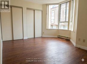 Toronto (Bay Street Corridor) condo for rent - A room with wooden floors and a window showing a building outside.