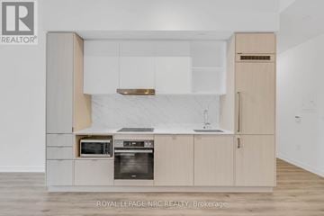 Toronto (Waterfront Communities) condo for rent - A modern kitchen with wooden cabinets and a marble backsplash.