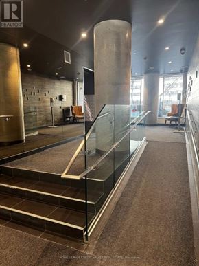Toronto (High Park North) condo for rent - A glass staircase with a metal railing and a brown carpeted floor.
