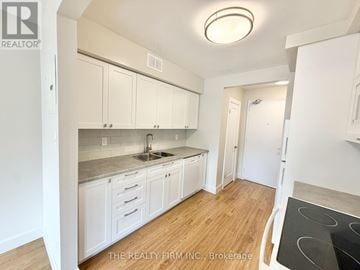 London South (South F) condo for rent - A kitchen with white cabinets and a stove top oven.