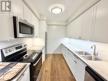 London South (South F) condo for rent - A kitchen with white cabinets and a black microwave.