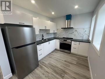 Fort Erie (Central) multi-family for rent - A kitchen with a stainless steel refrigerator and white cabinets.