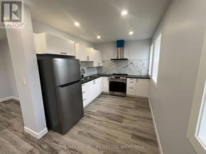 Fort Erie (Central) multi-family for rent - A modern kitchen with a black refrigerator and wooden flooring.