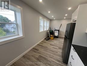 Fort Erie (Central) multi-family for rent - A room with a window, a vacuum cleaner, and a refrigerator.