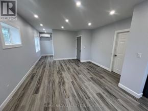 Fort Erie (Central) multi-family for rent - A spacious room with wood flooring and white walls.