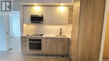 Vaughan (Vaughan Corporate Centre) condo for rent - A kitchen with wooden cabinets and a stainless steel oven.