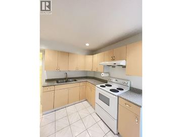 Burnaby apartment for rent - A kitchen with a white stove top oven and a sink.