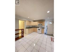 Burnaby apartment for rent - A kitchen with white tiled floors and wooden cabinets.