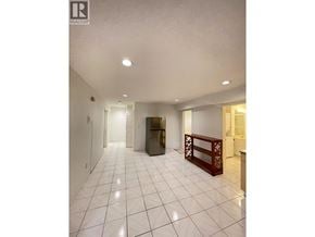 Burnaby apartment for rent - A spacious room with white tiled flooring and a refrigerator in the corner.