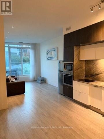 Toronto (Waterfront Communities) condo for rent - A modern kitchen with white cabinets and a black countertop.