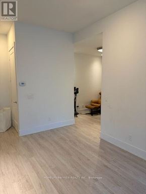 Toronto (Waterfront Communities) condo for rent - A room with white walls and wooden flooring, with a brokerage sign in the bottom left corner.