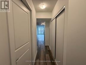Toronto (Yorkdale-Glen Park) condo for rent - A hallway with white walls and wood flooring leading to a door.