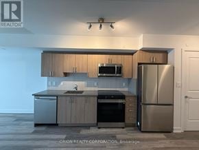 Toronto (Yorkdale-Glen Park) condo for rent - A modern kitchen with stainless steel appliances and wooden cabinets.