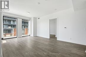 Toronto (Thorncliffe Park) condo for rent - A spacious room with wooden flooring and a large window overlooking a brick building.