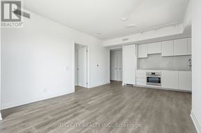 Toronto (Thorncliffe Park) condo for rent - A spacious, empty room with a kitchen area in the background.
