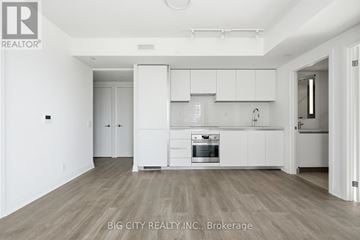 Toronto (Thorncliffe Park) condo for rent - A spacious kitchen with white cabinets and a wooden floor.