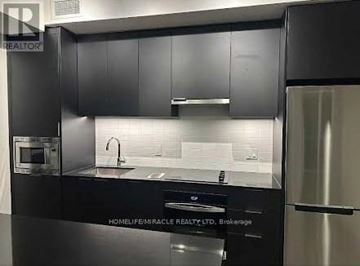 Oakville (Jm Joshua Meadows) condo for rent - A modern kitchen with black cabinets and stainless steel appliances.