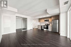Toronto (Humber Heights) condo for rent - A spacious kitchen with dark wood floors and white walls.