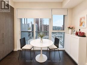 Toronto (Waterfront Communities) condo for rent - A dining room with a table and chairs and a view of the city.