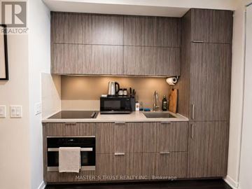 Toronto (Waterfront Communities) condo for rent - A kitchen with wooden cabinets and a stainless steel oven.