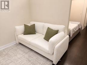 Toronto (Waterfront Communities) condo for rent - A white couch with two green pillows sits in a room.