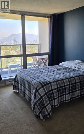 Vancouver apartment for rent - A bedroom with a bed, a chair, and a window overlooking a cityscape.