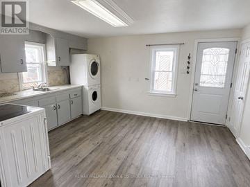 Ottawa multi-family for rent - A kitchen with white cabinets and a wooden floor.