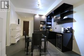 Toronto (Bay Street Corridor) condo for rent - A modern kitchen with black and white decor and a dining table with chairs.