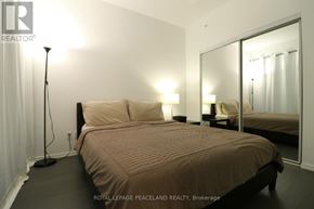 Toronto (Bay Street Corridor) condo for rent - A bedroom with a bed, two lamps, and a mirror.