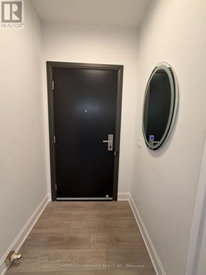Markham (Unionville) condo for rent - A hallway with a black door and a round mirror on the wall.