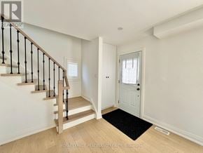 Toronto (Clairlea-Birchmount) apartment for rent - A hallway with a wooden staircase and a white door.