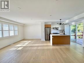 Toronto (Clairlea-Birchmount) apartment for rent - A spacious, empty room with wooden flooring and a kitchen area in the background.