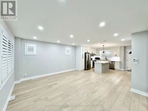 Toronto (Briar Hill-Belgravia) apartment for rent - A spacious room with wooden flooring and a kitchen area in the background.