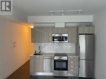 Toronto (Bay Street Corridor) condo for rent - A modern kitchen with stainless steel appliances and a wooden cabinet.