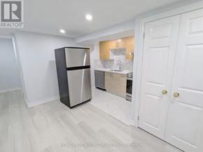 Toronto (Greenwood-Coxwell) apartment for rent - A kitchen area with a refrigerator, sink, and cabinets.