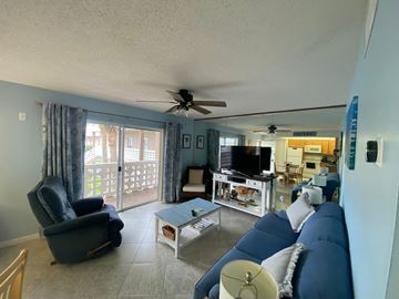 Cocoa Beach apartment for rent - A living room with a blue couch and a ceiling fan.