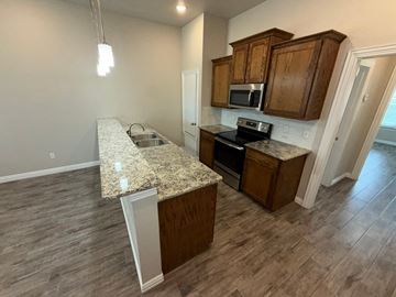 Temple townhouse for rent - A kitchen with a granite countertop and wooden cabinets.