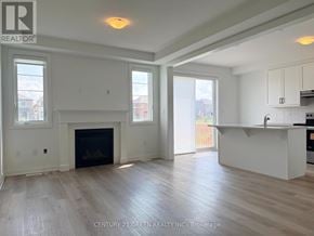 Milton (Bw Bowes) townhouse for rent - A spacious living room with a fireplace and a kitchen area in the background.